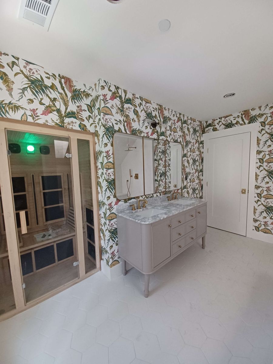 Bathroom with a botanical bird-and-branch wallpaper, a grey vanity and a glass steam-room door