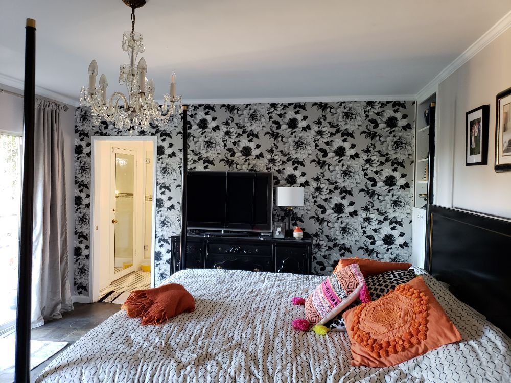 Bedroom with black-and-white floral damask wallpaper, a crystal chandelier and a four-poster bed