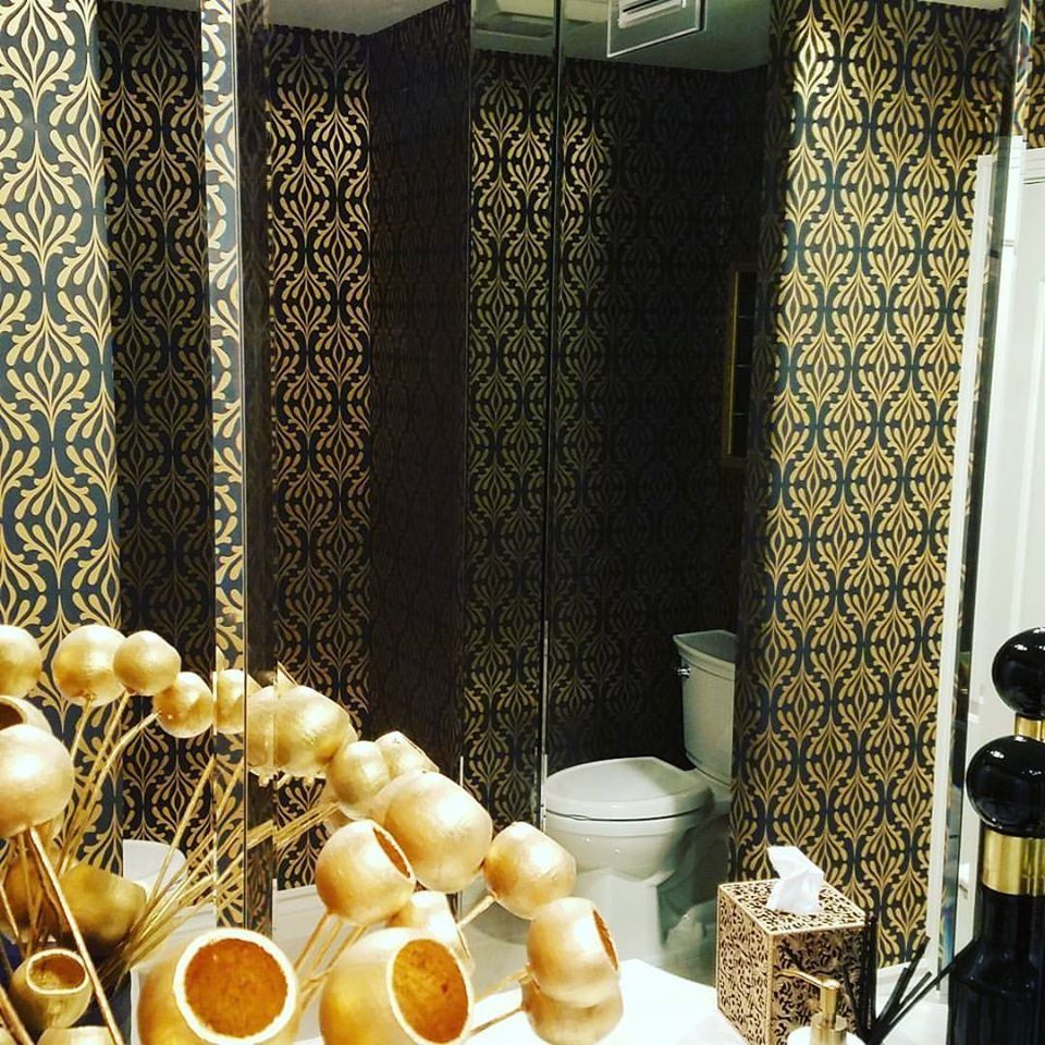 Bathroom with black and metallic gold art deco wallpaper and a bowl of gold ornaments