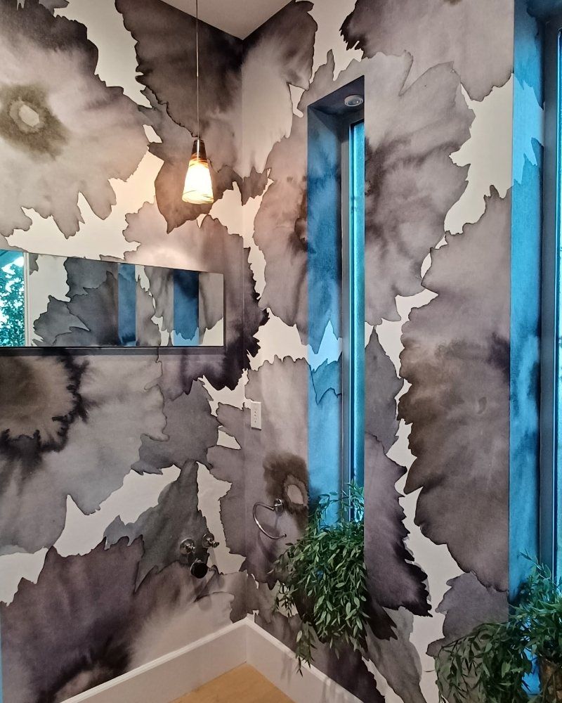 Bathroom with a black ink-wash floral mural, a pendant light and a mirror reflecting a blue-framed window