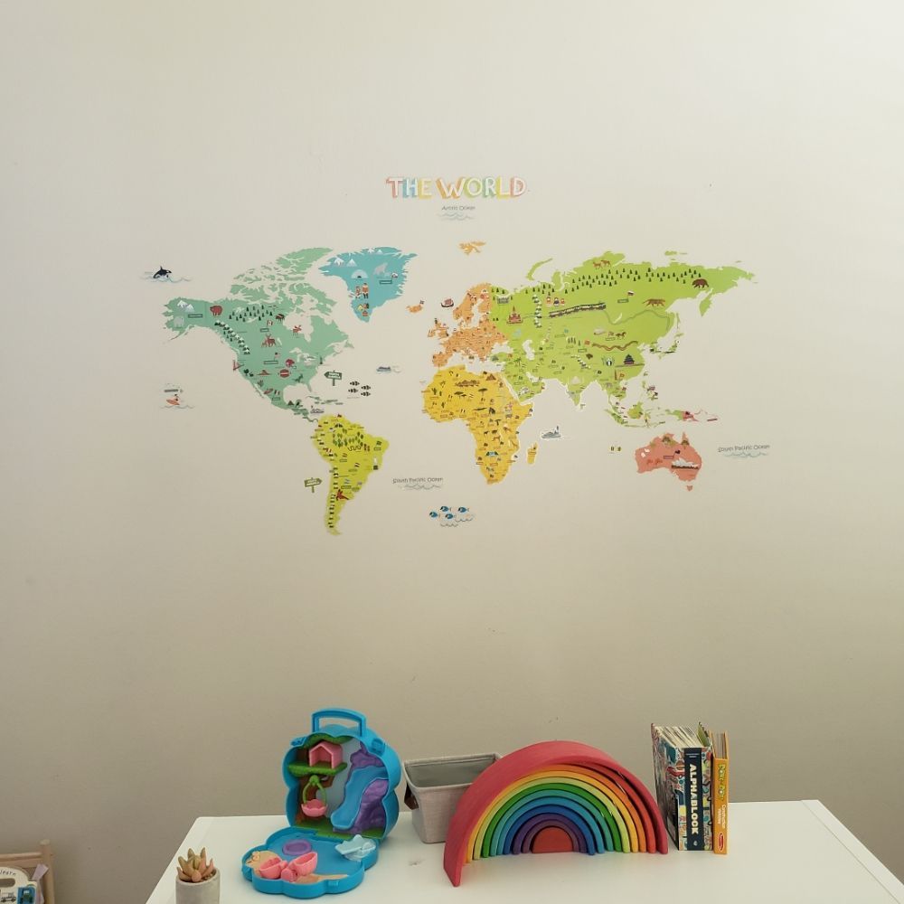 Nursery wall with a colorful illustrated world map mural above a toy shelf